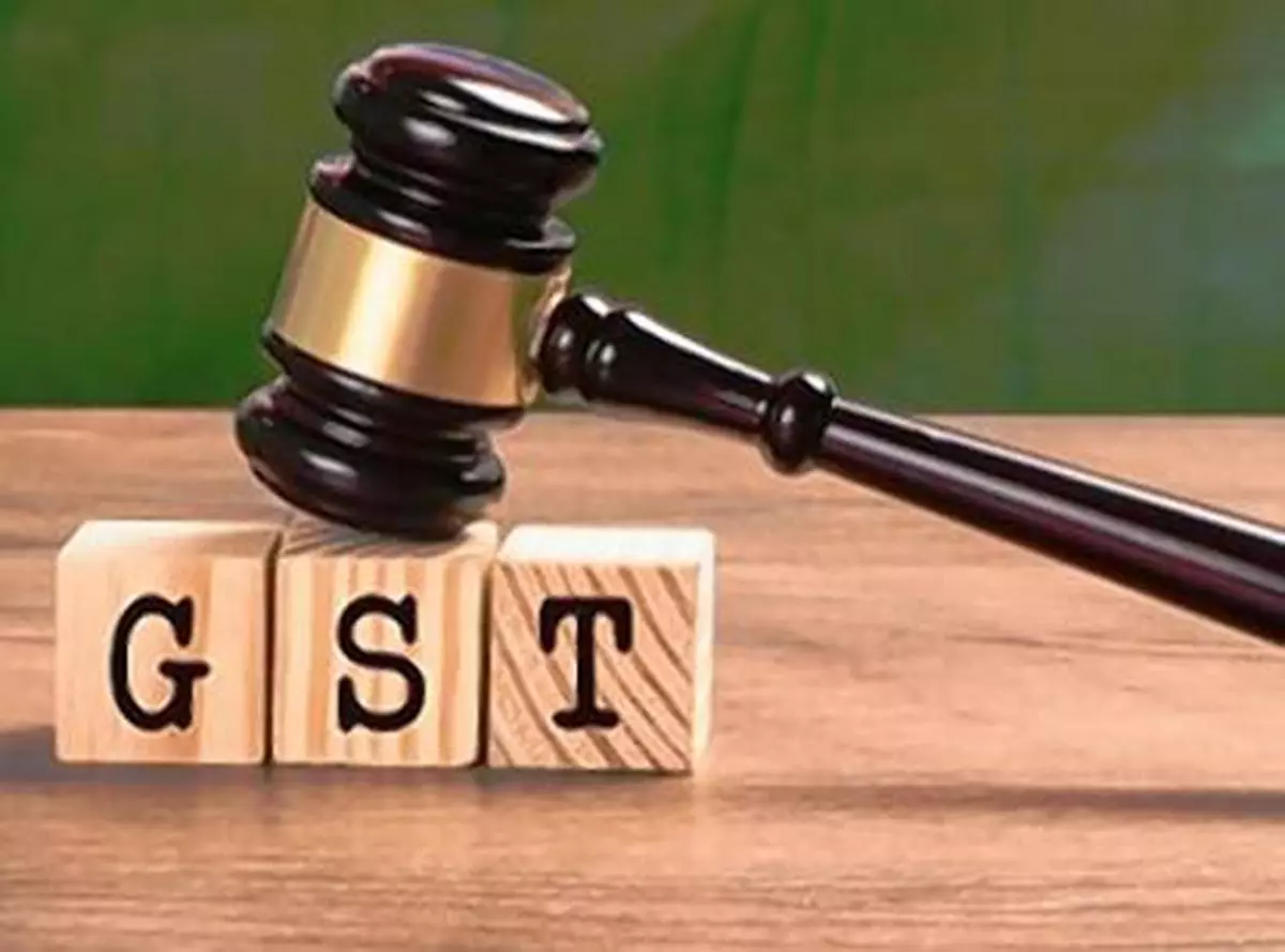 Stock photo of GST low in india. GST text written over wooden blocks with wooden gavel over it and indian national flag or tricolour in the background, selective focus