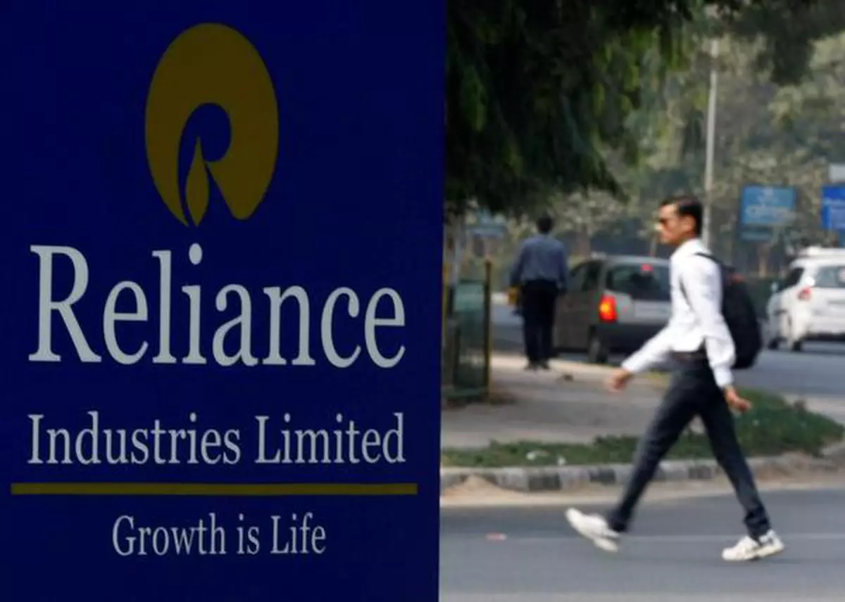 FILE PHOTO: A man walks past a Reliance Industries Limited sign board installed on a road divider in the western Indian city of Gandhinagar January 17, 2014. Indian energy conglomerate Reliance Industries reported a nearly flat profit of 55.11 billion rupees ($895 million) for the December quarter but beat analyst estimates, helped by stable margins in its main refining business. REUTERS/Amit Dave (INDIA - Tags: BUSINESS ENERGY)/File Photo