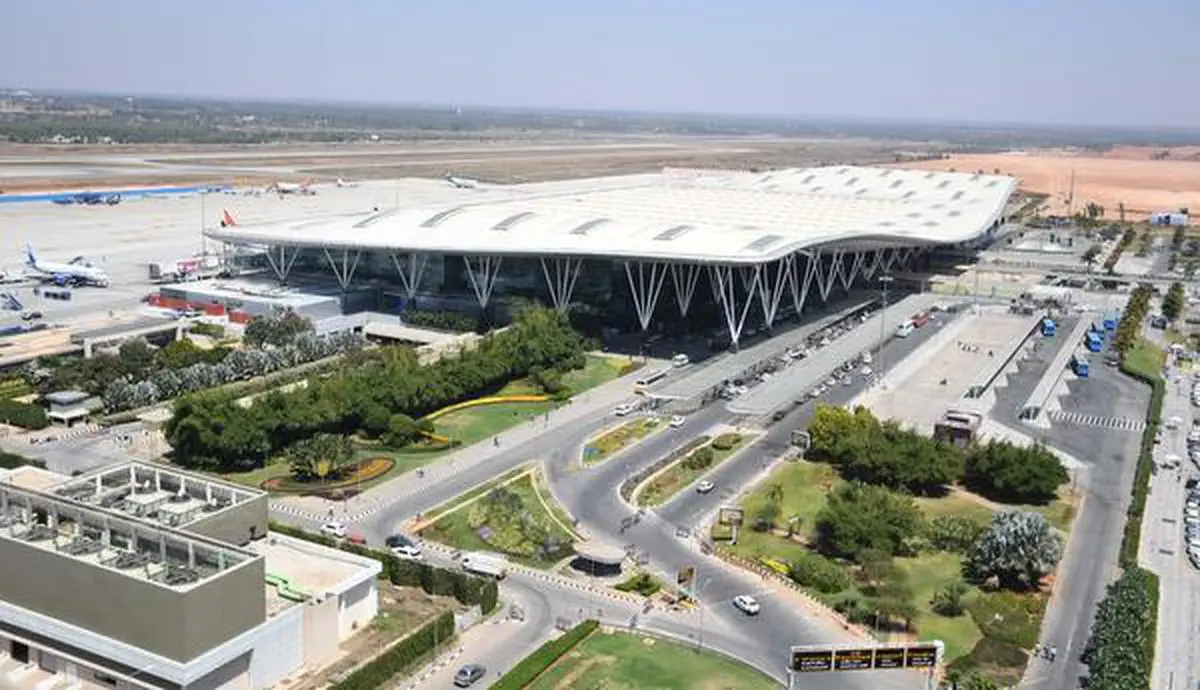 Passengers wait next to a giant suitcase outside the terminal building of  Bengaluru International Airport at its opening in Devanahalli, on the  outskirts of Bangalore, India, Friday, May 23, 2008. The Bengaluru