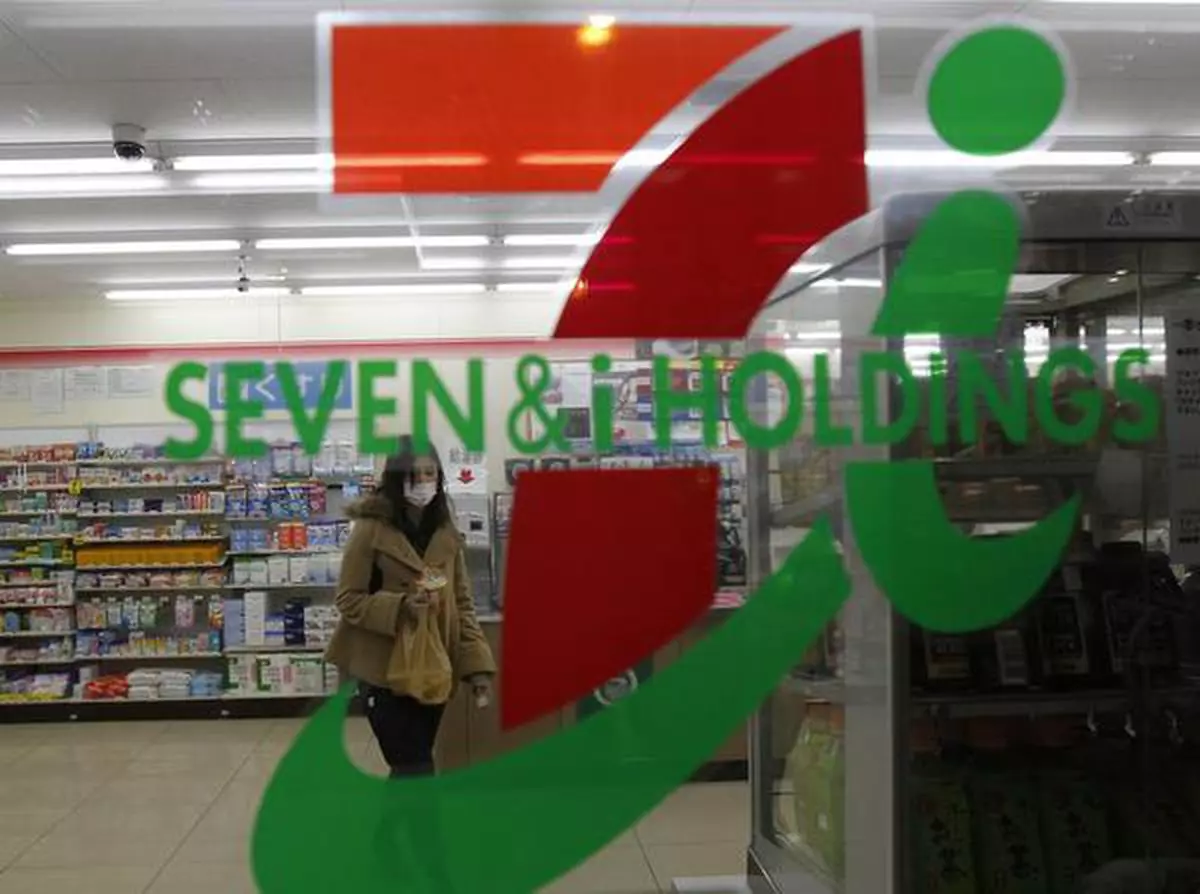 A shopper is seen behind Seven & I Holdings' logo at a Seven-Eleven convenience store in Tokyo January 6, 2011. Seven & I Holdings, Japan's top retailer, posted a 7.4 percent rise in quarterly operating profit, helped by higher revenue from its core convenience store segment, and kept its annual outlook unchanged. REUTERS/Kim Kyung-Hoon (JAPAN - Tags: BUSINESS)