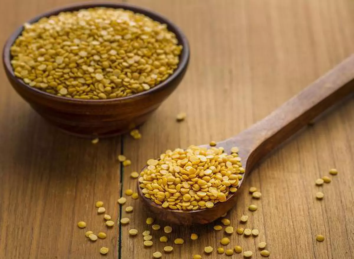 toor dal or arhar dal or raw pulses in wooden spoon and bowl