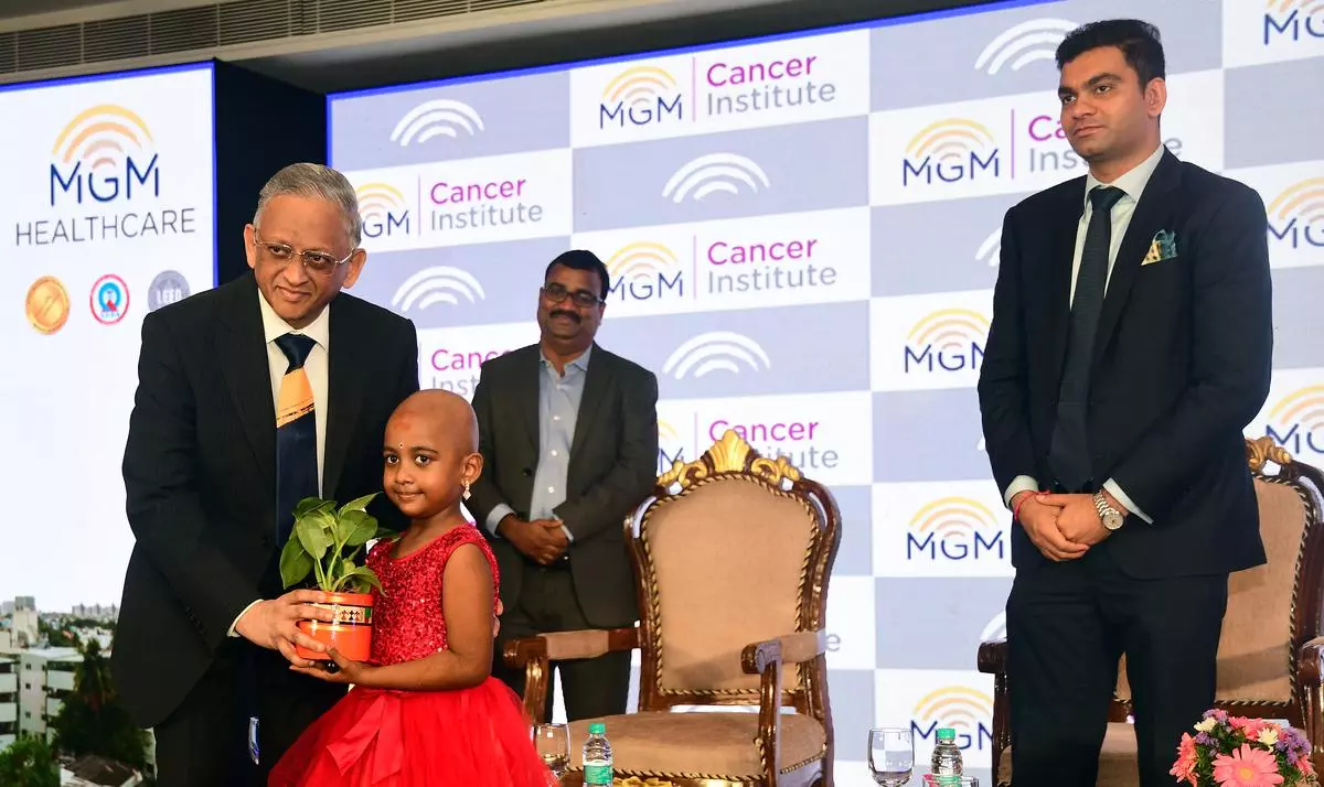 M.A. Raja, Director, Oncology Services and chairman, Medical Services Board, MGM Healthcare, presenting a potted plant to a young cancer survivor, at the launch of MGM Cancer Institute. Prashanth Rajagopalan, Director, MGM is seen on the right.