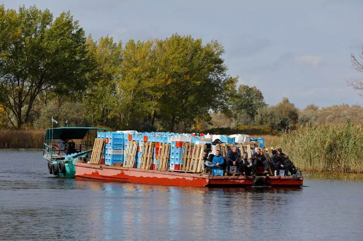  Men sit on the deck of a cargo boat departing from the town of Oleshky, in the course of Russia-Ukraine conflict in Kherson region, Russian-controlled Ukraine. 