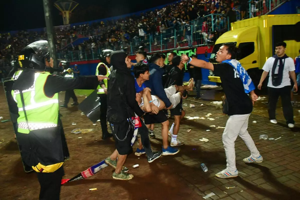 Supporters evacuate a man due to tear gas fired by police during the riot after the football match between Arema vs Persebaya at Kanjuruhan Stadium, Malang, East Java province, Indonesia.