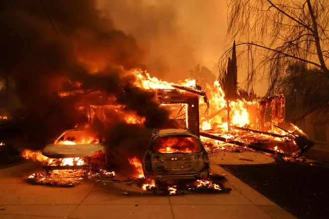 Vehicles and a house burn as powerful winds fueling devastating wildfires in the Los Angeles area force people to evacuate, at the Eaton Fire in Altadena, California, U.S. January 8, 2025.