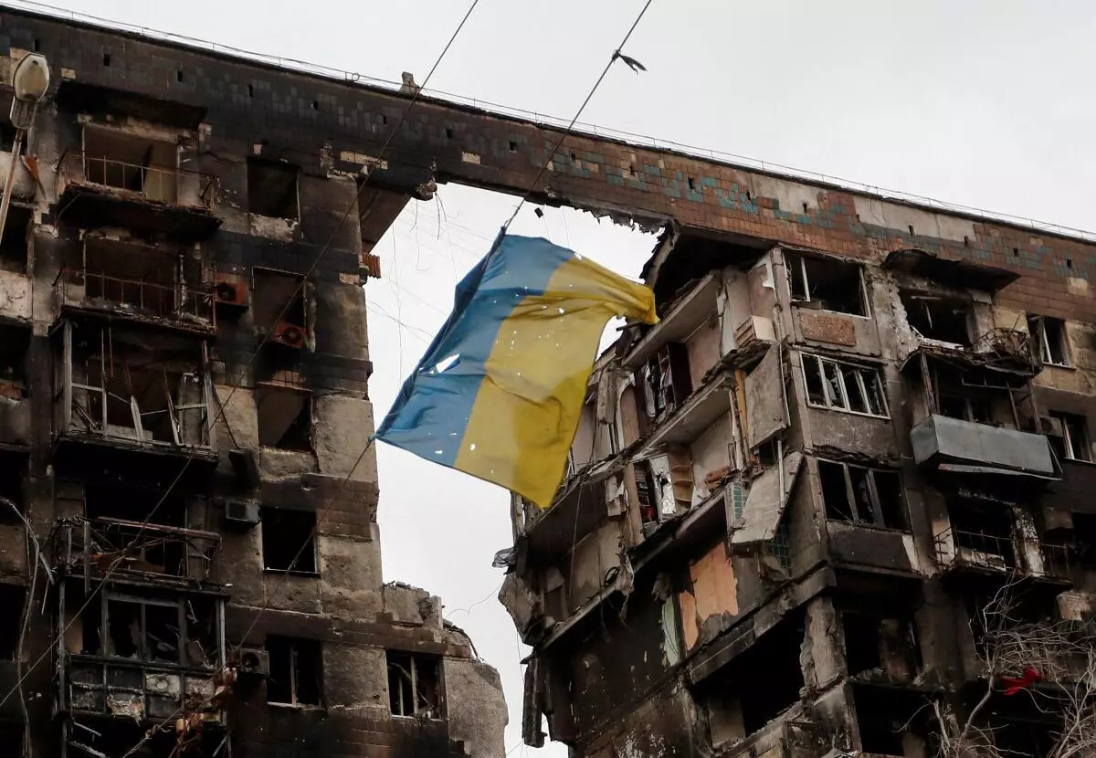 A view shows a torn flag of Ukraine hung on a wire in front an apartment building destroyed during Ukraine-Russia conflict in the southern port city of Mariupol, Ukraine April 14, 2022