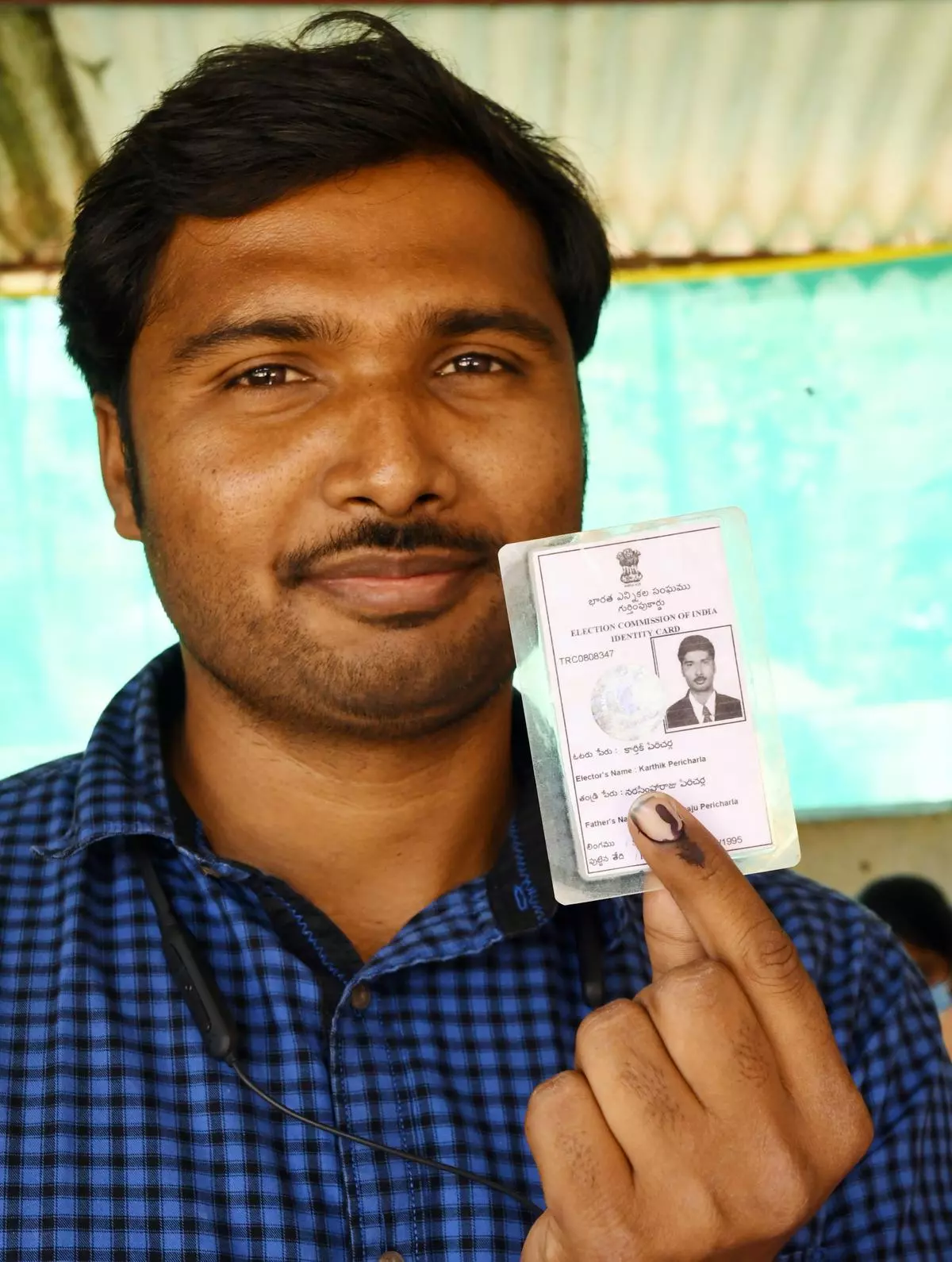A man holds up his voter id card in front of the camera.
