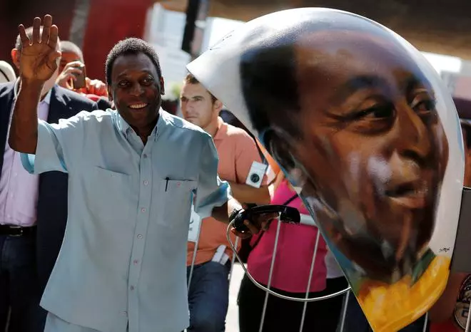 FILE PHOTO: Brazilian soccer legend Pele waves next to a public telephone booth with an image of his face painted by Brazilian artist Sipros after he autographed it, during the Call Parade art exhibition in Sao Paulo, Brazil, May 8, 2014.  REUTERS/Nacho Doce/File Photo