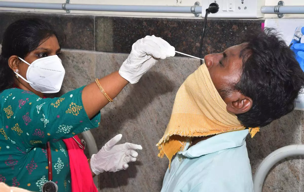 A medical professional collects sample from a person for Covid-19 test at GGH, Vijayawada, on Friday.