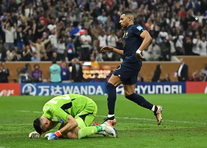 Argentina’s Emiliano Martinez reacts as France’s Kylian Mbappe celebrates scoring their first goal.
