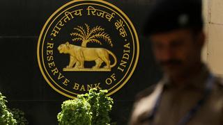 A police officer walks past the Reserve Bank of India (RBI) logo inside its headquarters in Mumbai