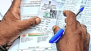 A person holds up the Aadhaar card. A person holds up the Aadhaar card.