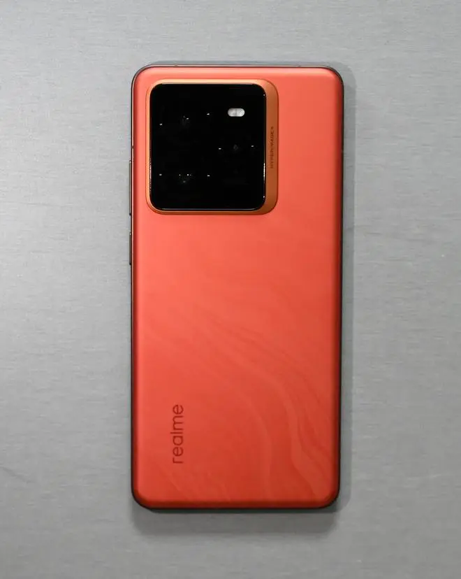 The Mars Orange variant features a bright orange back with slender etched motifs and a black panel housing the triple camera setup. 