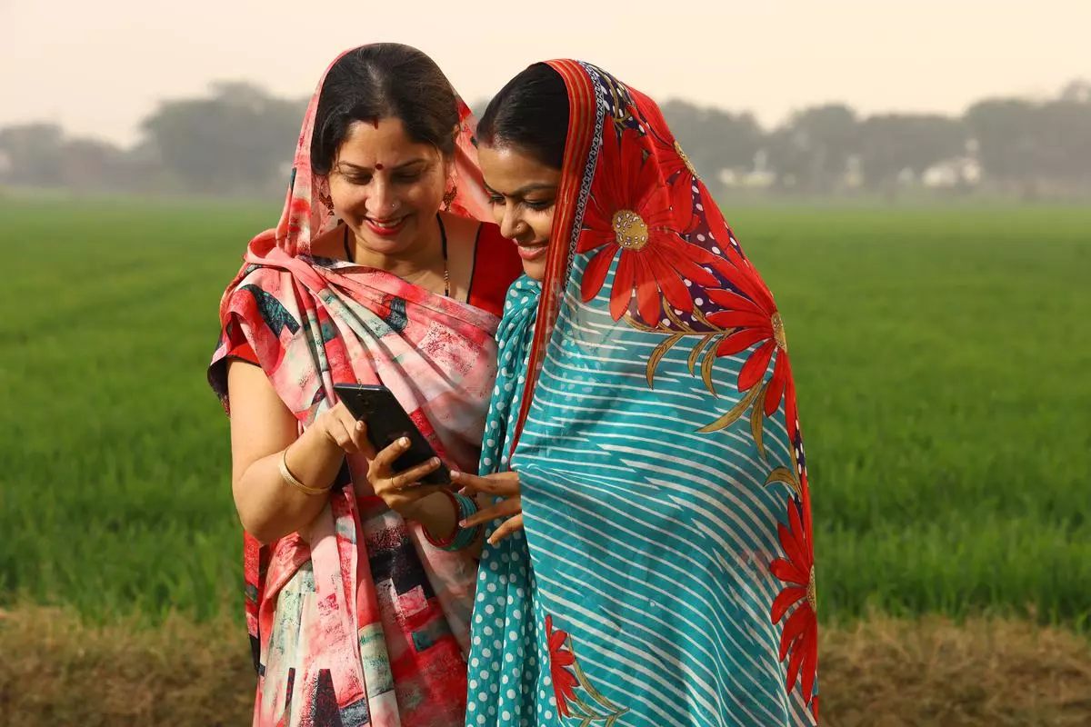 Indian Rural farmer women using phone in the field and learning technology.