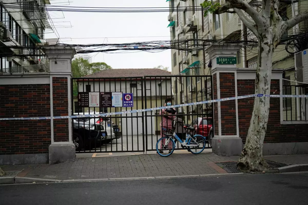 A resident stands behind a gate blocking an entrance to a residential area under lockdown amid the coronavirus disease (COVID-19) pandemic, in Shanghai, on Wednesday 