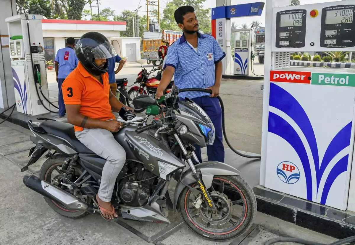 A fuel station attendant pumps petrol into a two-wheeler at a filling station in Nadia