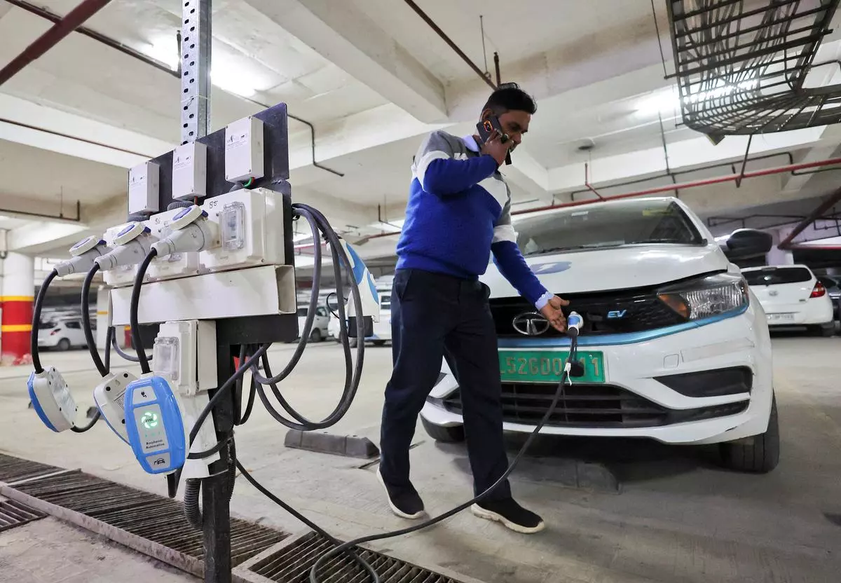 A man charges an electric vehicle (EV) at a charging hub in Gurugram
