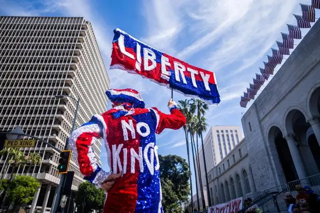 A demonstrator holds a sign and waits outside City Hall for a 'No Kings' protest against U.S. President Donald Trump's administration policies, in Los Angeles, California, U.S., March 28, 2026.