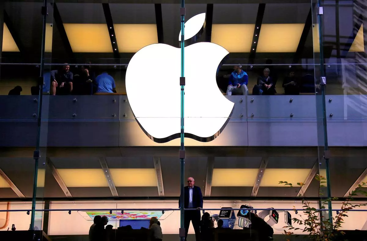 A person stands underneath an illuminated Apple logo.