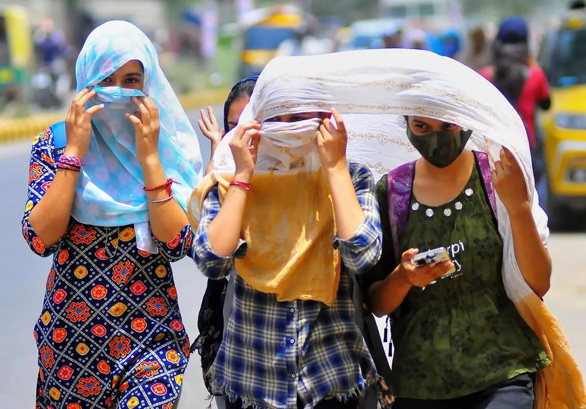 Women cover themselves with scarves on a hot summer day, in Gurugram
