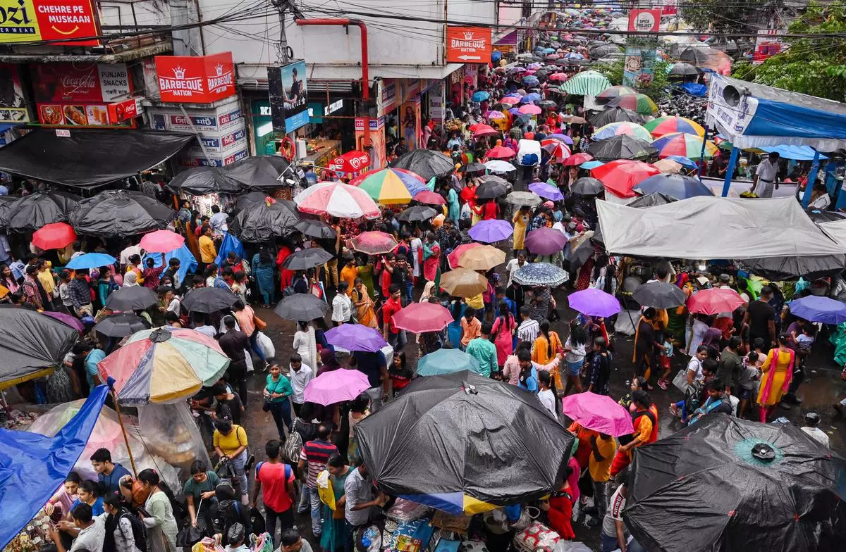 People holding umbrellas walk at a market amid monsoon rains, in Kolkata