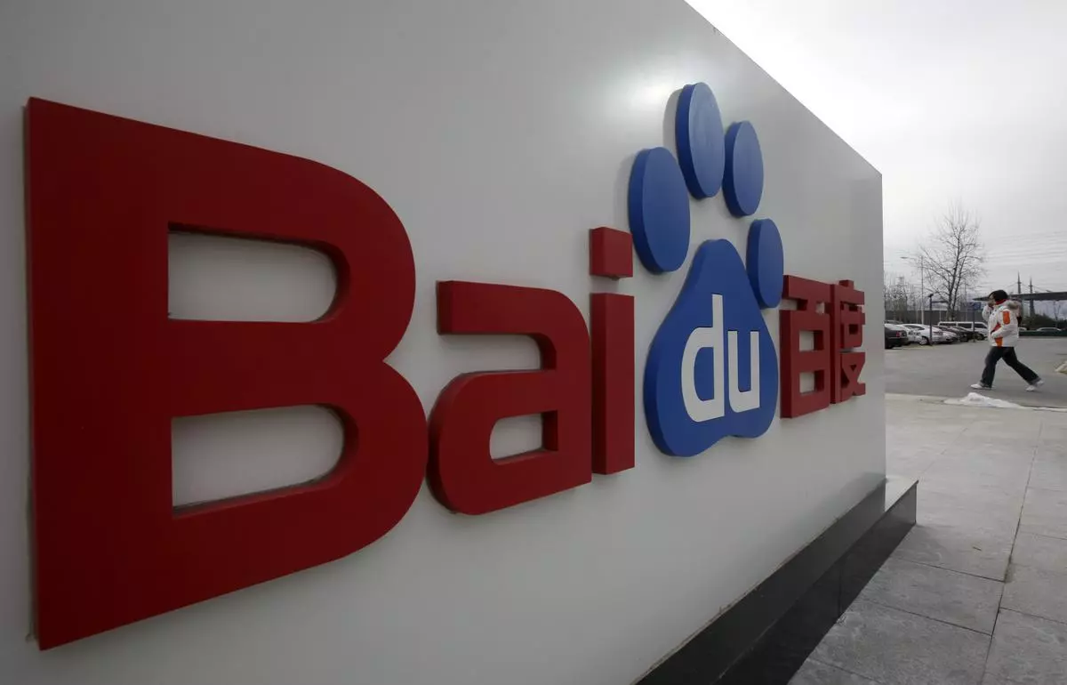 A woman walks past the company logo of Baidu.
