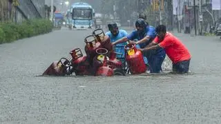 Mumbai: People move a cart with domestic gas cylinders through a waterlogged road following rainfall, in Mumbai, Monday, Aug. 18, 2025. 