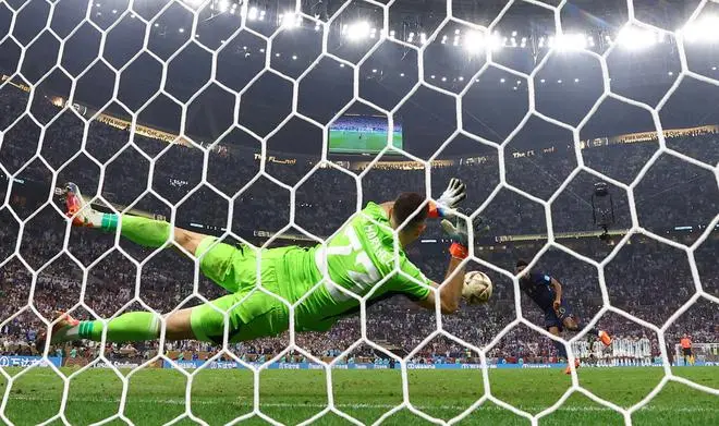 Emiliano Martinez of Argentina saves a penalty from Kingsley Coman of France during the penalty shootout