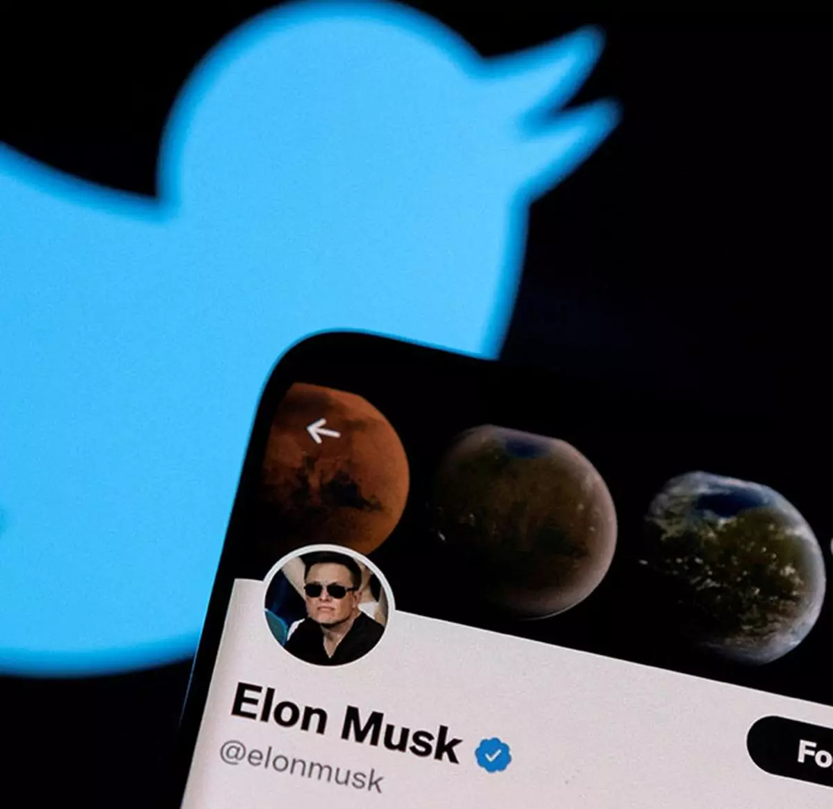 Elon Musk’s Twitter account is seen on a smartphone in front of the Twitter logo in this photo illustration 