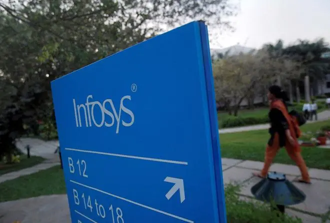 FILE PHOTO: An employees walks past a signage board in the Infosys campus at the Electronics City IT district in Bengaluru