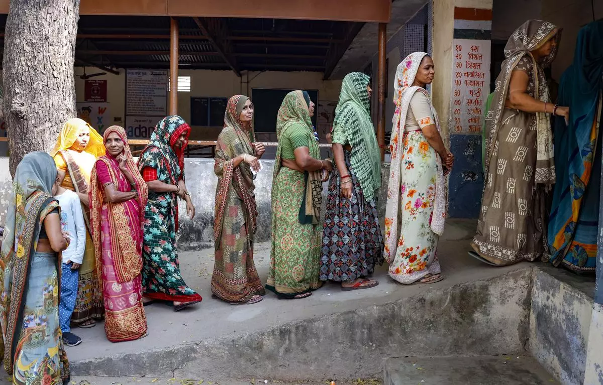 Women wait in a queue to cast their votes at a polling booth during the second and final phase of Gujarat Assembly elections, in Ahmedabad, on Monday