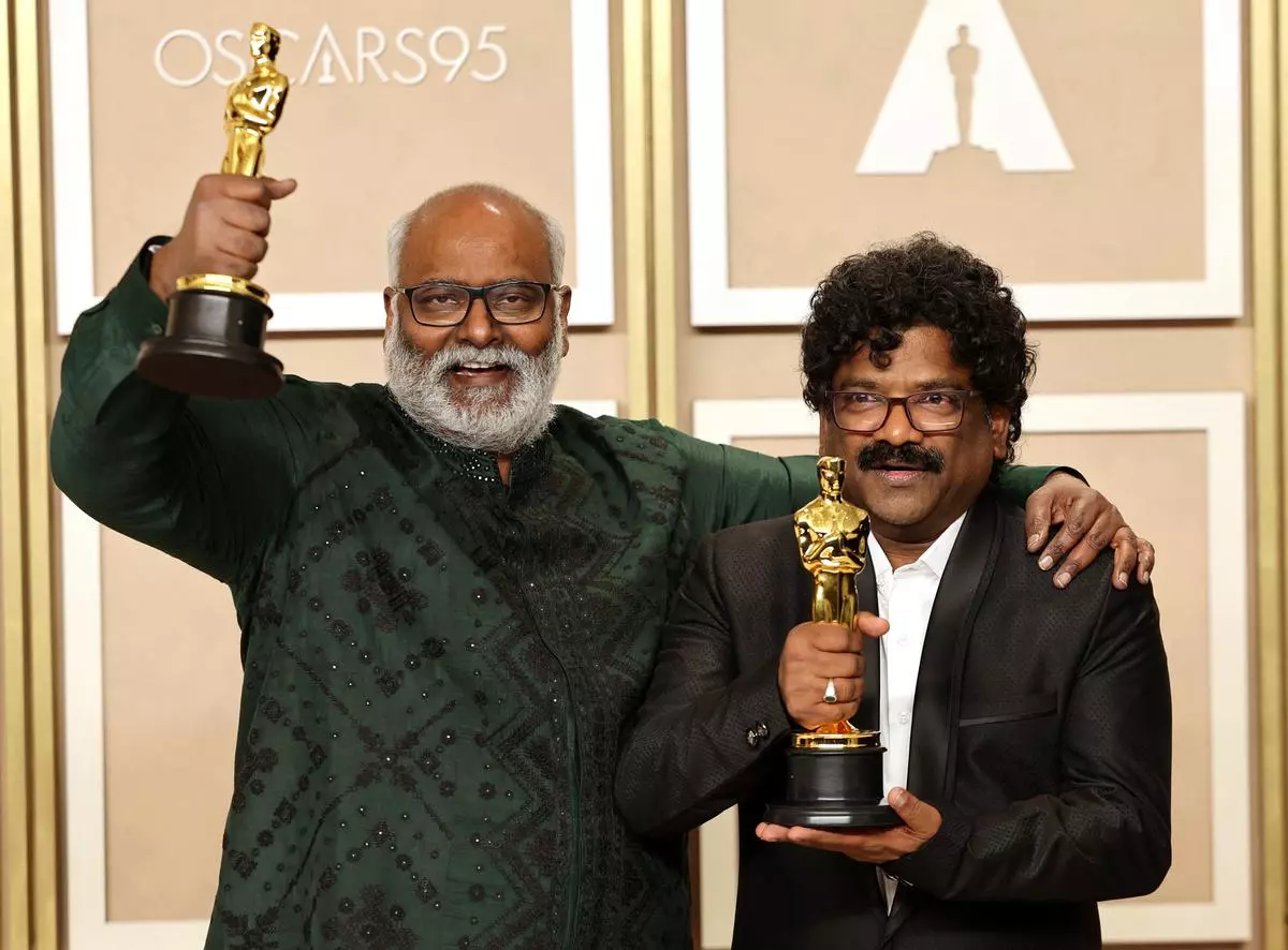 MM Keeravaani and Chandrabose pose with the Oscar for Best Original Song for “Naatu Naatu” from “RRR” in the Oscars photo room.