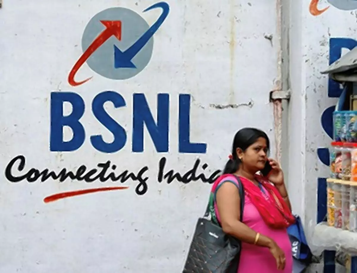 A woman speaks on her mobile phone in front of the logo of Bharat Sanchar Nigam Ltd (BSNL) painted on a wall outside its office in Kolkata,