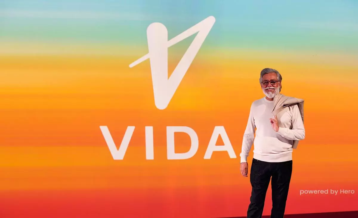 Pawan Munjal, Chairman and CEO, Hero MotoCorp, standing next to the Vida logo