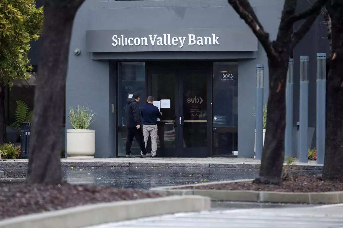 A man puts a sign on the door of the Silicon Valley Bank at the bank’s headquarters in Santa Clara, California.