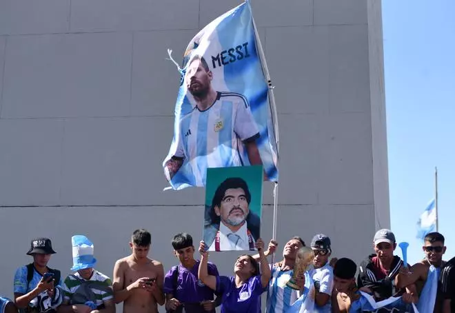 Argentina fans celebrate winning the World Cup with a flag of Argentina’s Lionel Messi and a picture of Diego Maradona.