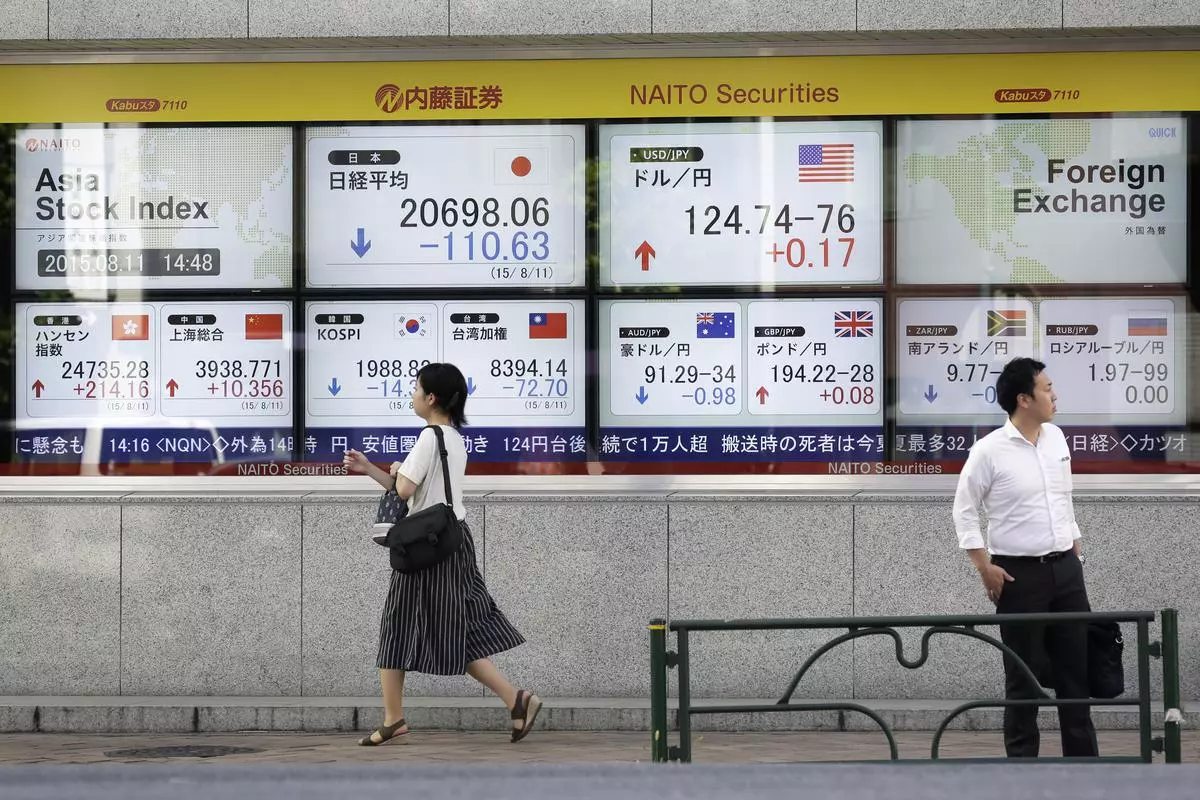 Pedestrians walk past an electronic stock board displaying Asian stock indexes including the Nikkei 225 Stock Average