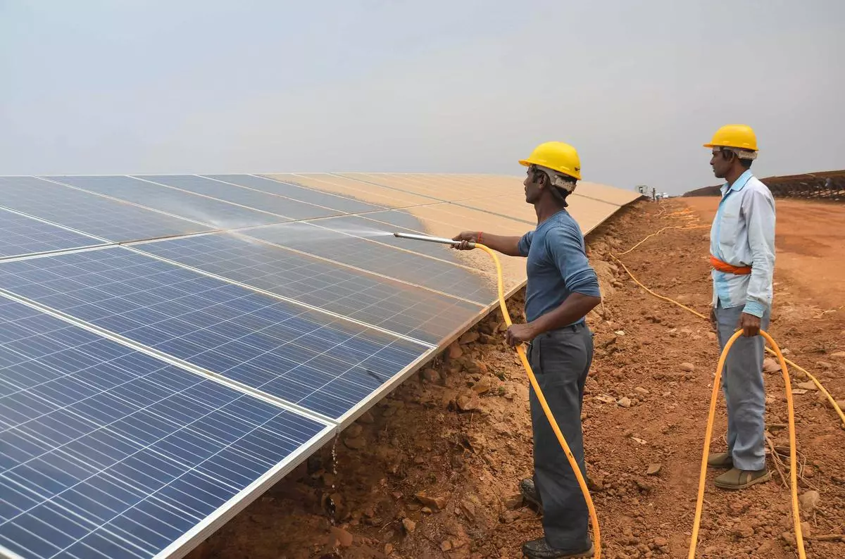 Green initiative: Workers spray water to clear dust gathered over the solar electric panels 