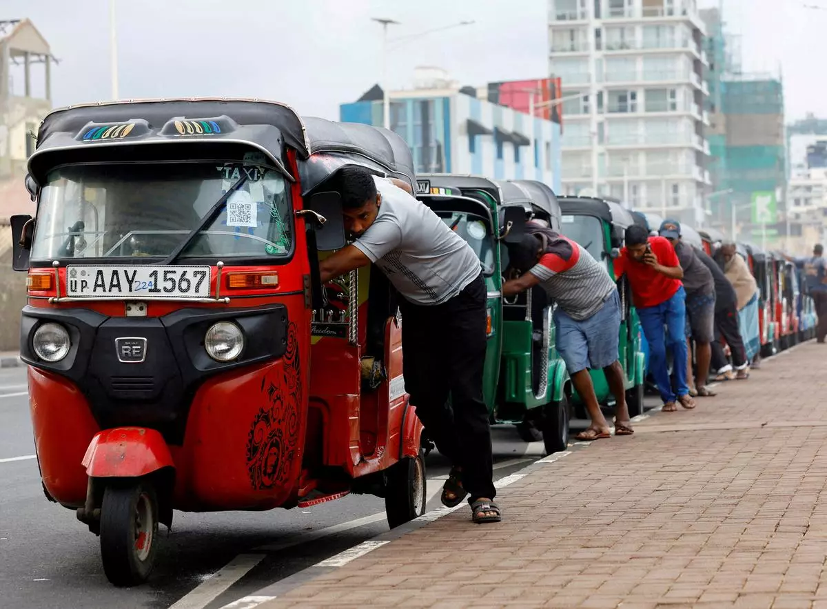 Drivers push auto rickshaws in a line to buy petrol from a fuel station, amid Sri Lanka’s economic crisis, in Colombo 