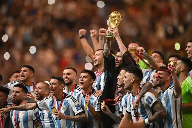 Argentina’s Lionel Messi lifts the World Cup trophy alongside teammates as they celebrate after winning the World Cup.