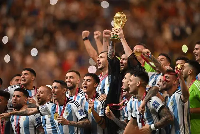 Lionel Messi of Argentina raises the World Cup trophy with teammates as they celebrate after winning the World Cup.