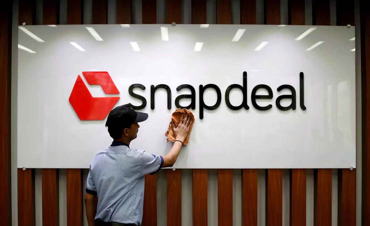 FILE PHOTO: An employee cleans a Snapdeal logo at its headquarters in Gurugram. REUTERS