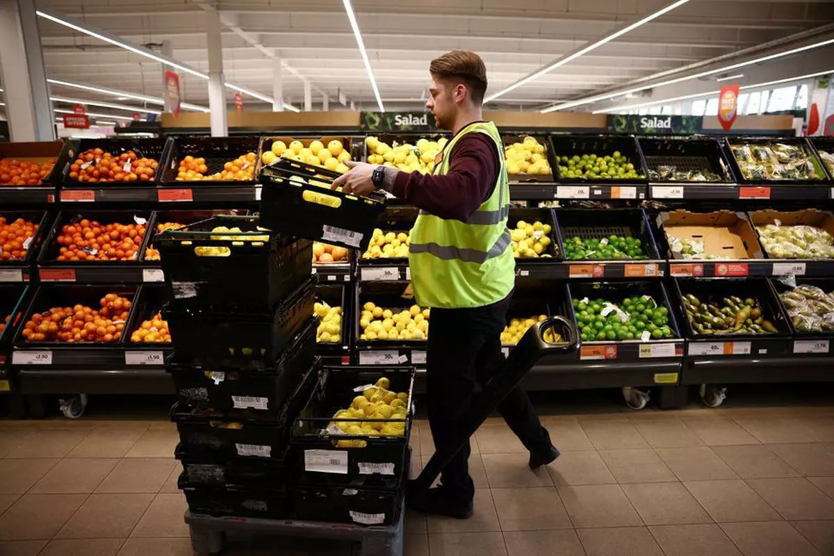A employee arranges produce inside a Sainsbury’s supermarket in Richmond, west London, Britain