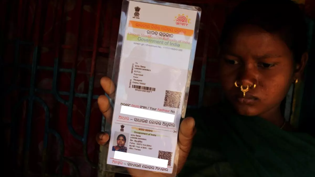 A tribal girl of Jhumuka village shows her Aadhaar card as she comes near to ration distribution centre for correction in Rayagada district of Odisha on January 14, 2018. Photo: Biswaranjan Rout