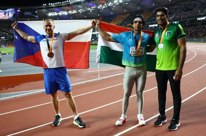 Gold medallist India’s Neeraj Chopra celebrates after the final with silver medallist Pakistan’s Arshad Nadeem and bronze medallist Czech Republic’s Jakub Vadlejch