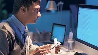 Man wiping glasses while reading information on the screen, the GUI has been changed digitally