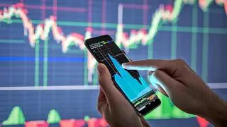 Businessman checking stock market data. He using a mobile phone. Analysis economy data on forex earn graph.