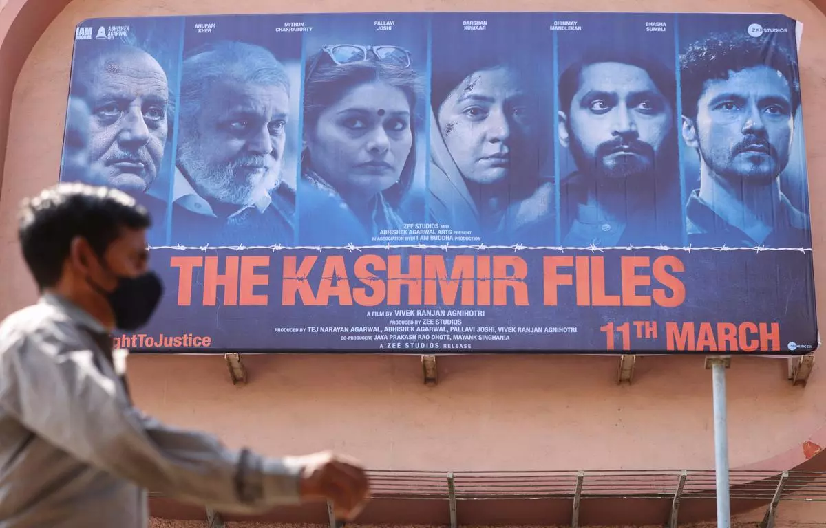 A man walks past a poster of Bollywood movie “The Kashmir Files” outside a cinema in Mumbai, India