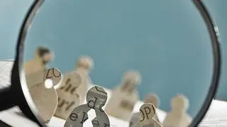 Business recruitment or hiring photo concept. Looking for talent. Icons of candidates are standing on open newspaper under magnifier.