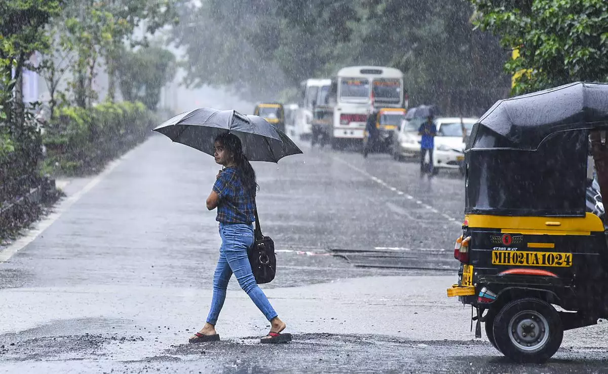 Mumbai: A woman holding an umbrella crosses a road amid monsoon rains, in Mumbai, Tuesday, Aug 16, 2022. - PTI